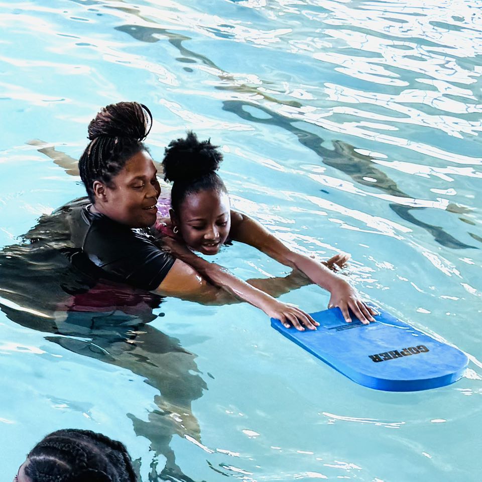 A woman teaching a girl how to swim.